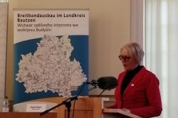Frau hält eine Rede an einem Podest. Dahinter ist eine Karte des Landkreises Bautzen.